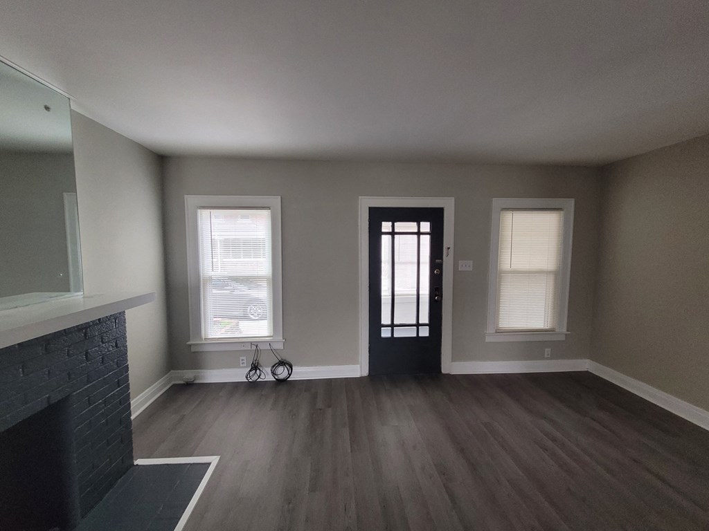 an empty living room with a fireplace and a black door
