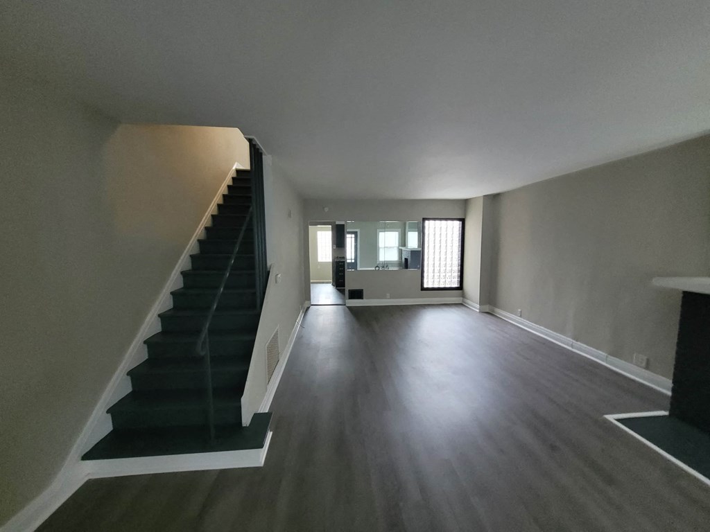 the living room and staircase of a house with a hard wood floor