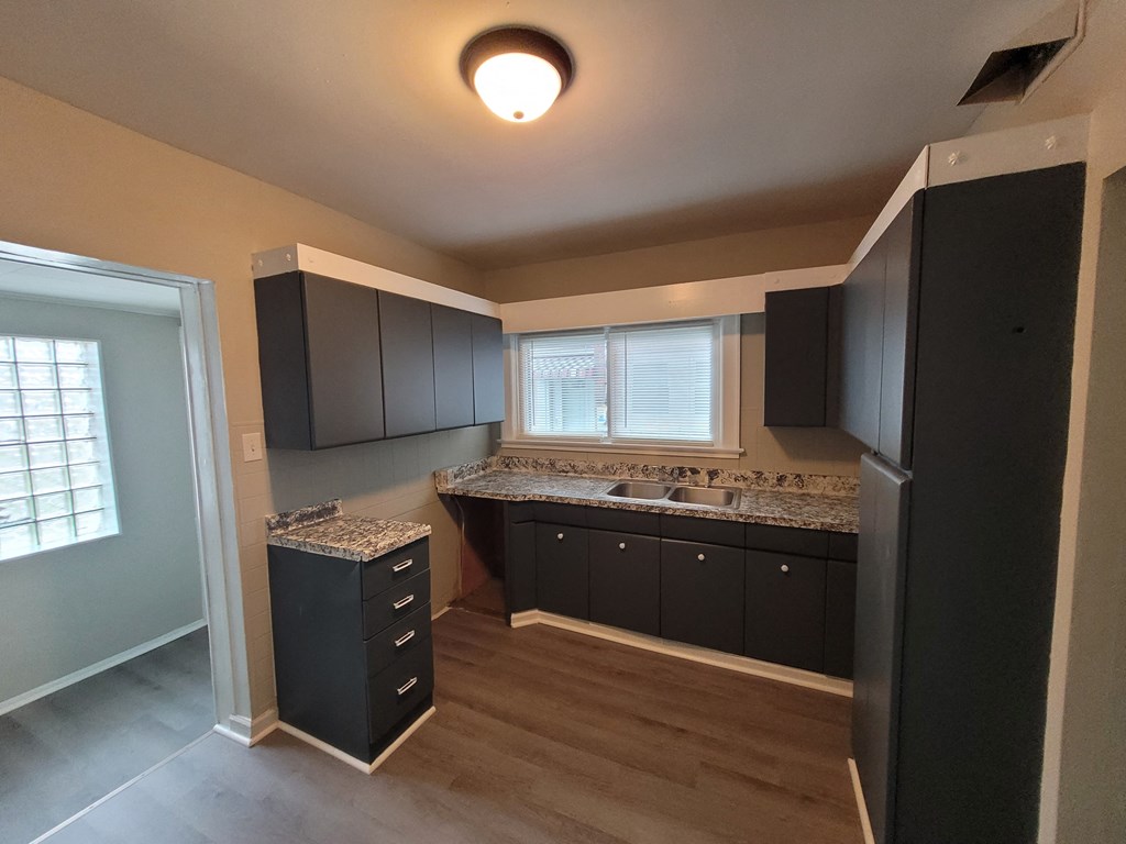 an empty kitchen with black cabinets and granite counter tops