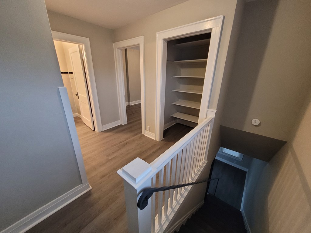 a stairwell in a home with a staircase and a book shelf and a closet