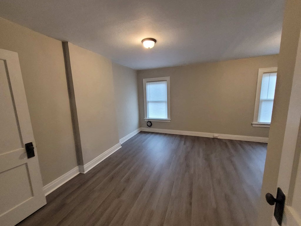a empty living room with a hard wood floor and a window