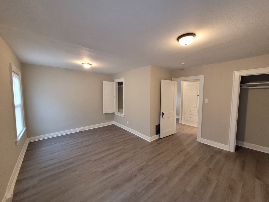 an empty living room with wood flooring and a door into a hallway