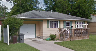 a yellow house with a porch and a white garage door