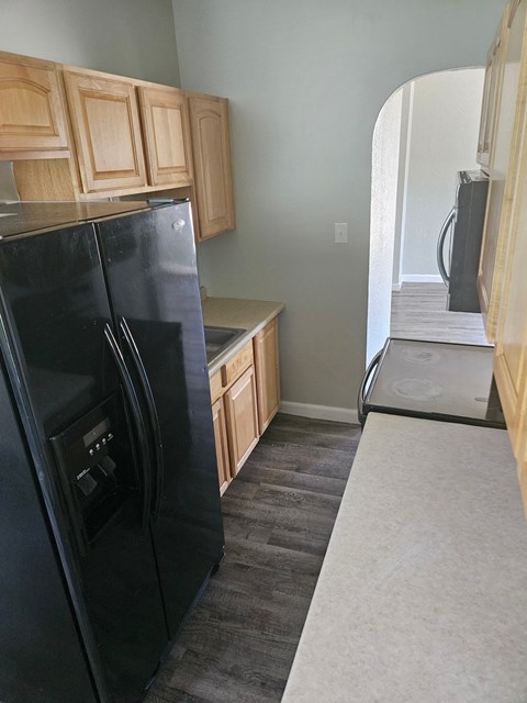 a kitchen with a black refrigerator and wooden cabinets
