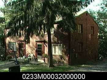 a red brick house with a tree in front of it