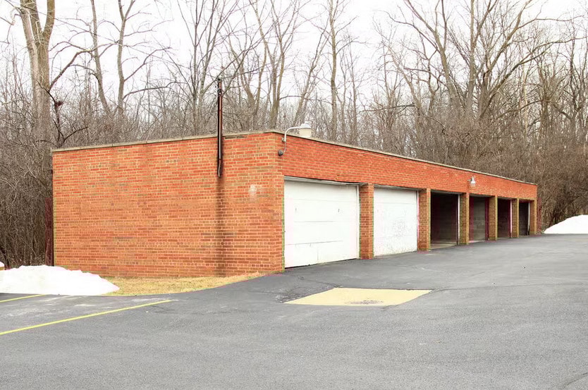 a brick building with white garage doors in a parking lot