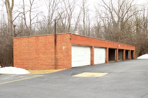 a brick building with white garage doors in a parking lot