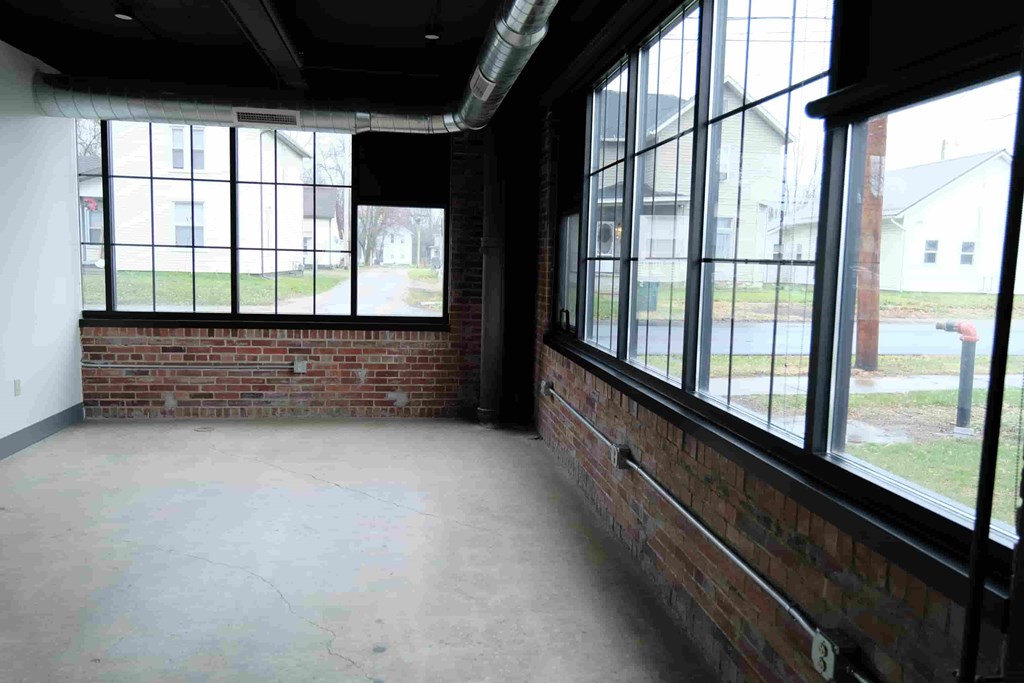 an empty room with a brick wall and large windows