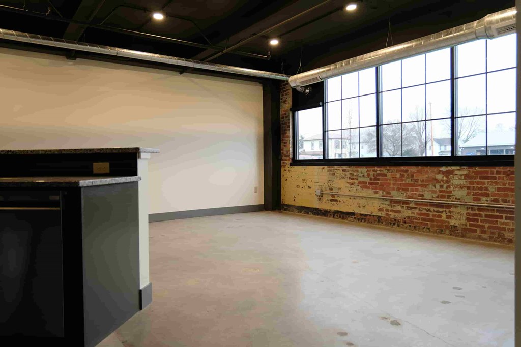 an empty room with a brick wall and large windows