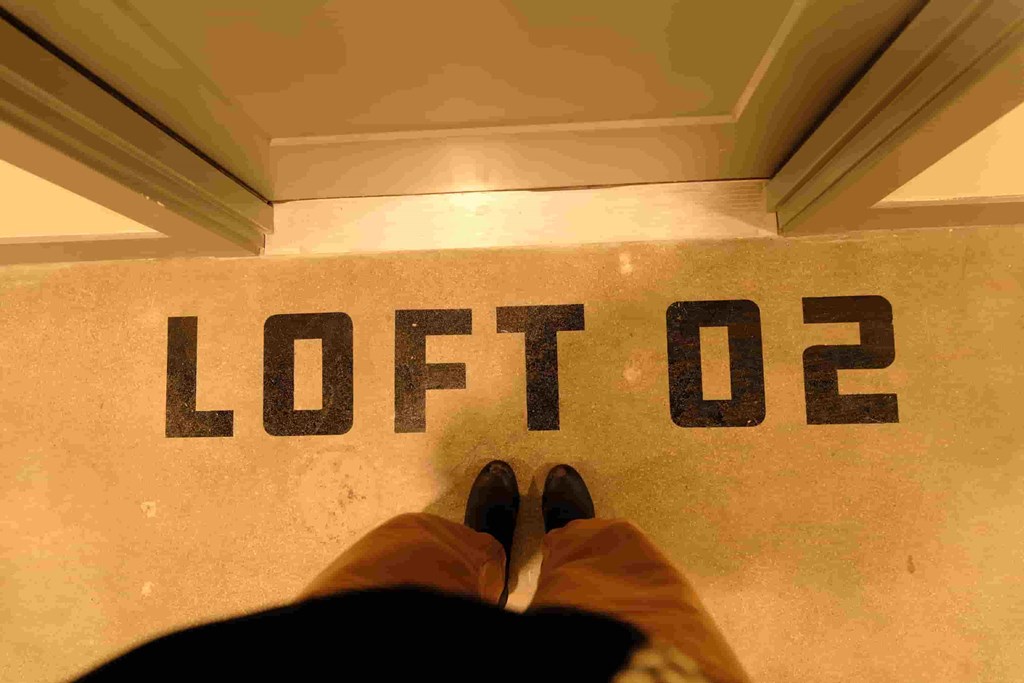 a person sitting on the floor of a hotel room with their feet on thefloor