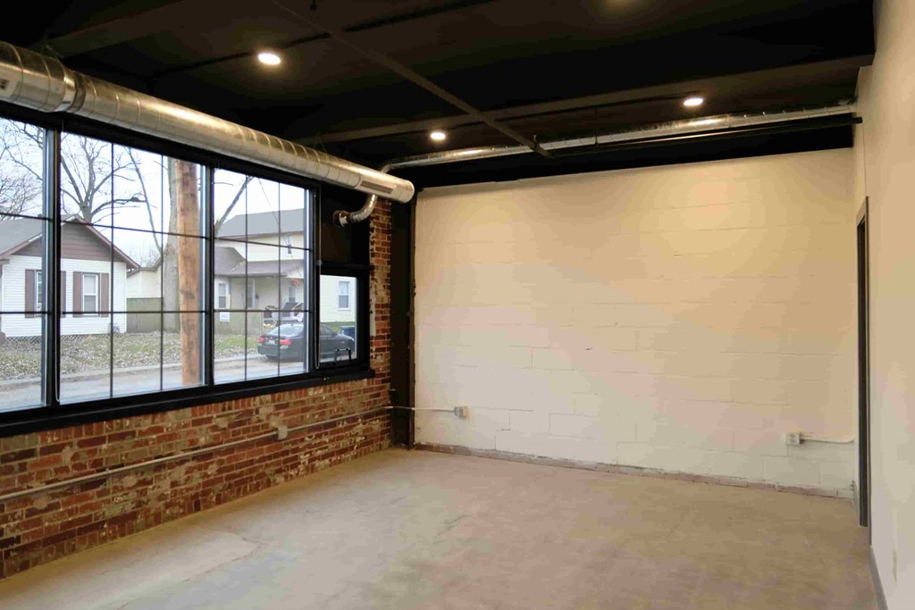 an empty room with a brick wall and a large window