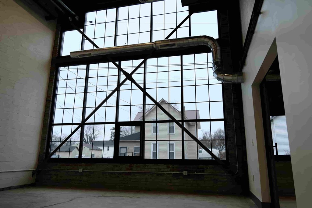 an empty room with a large window and a building in the background