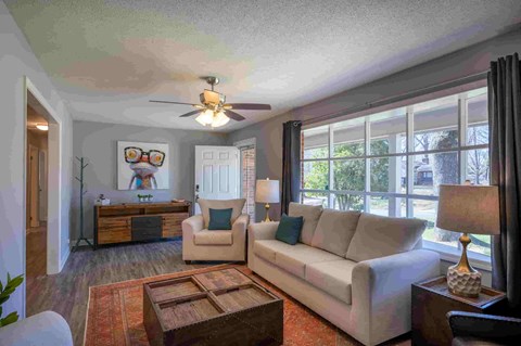 a living room with a couch and a chair and a ceiling fan