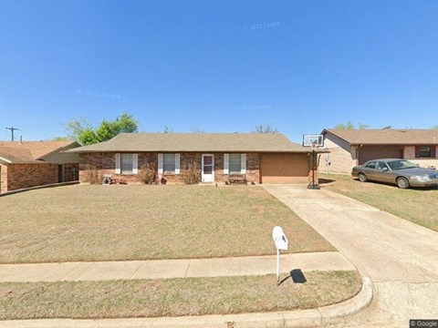 A house with a car parked in front and a sign in the front yard.