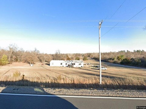 a view of a field with a road and a house