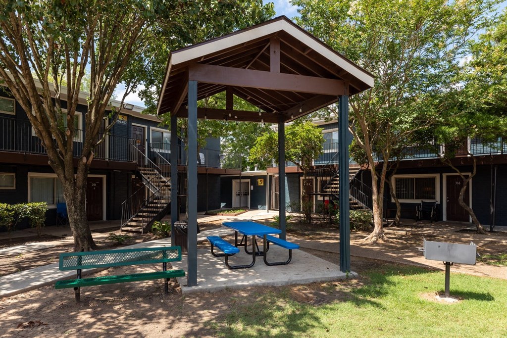 a picnic pavilion with benches and a picnic table in a park