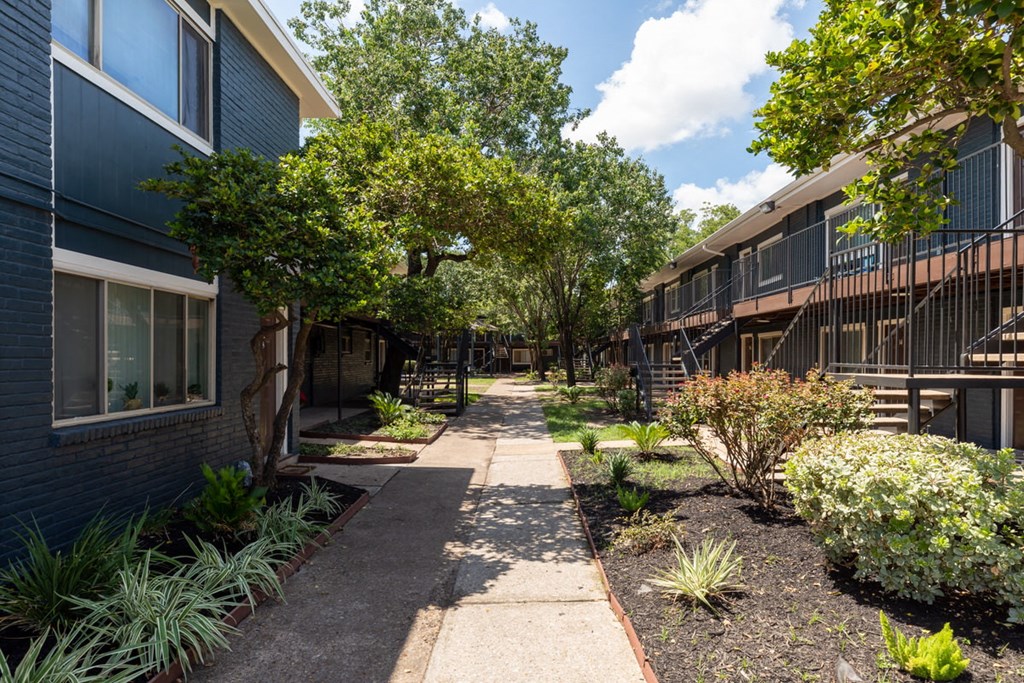 a walkway between two apartment buildings with trees and plants