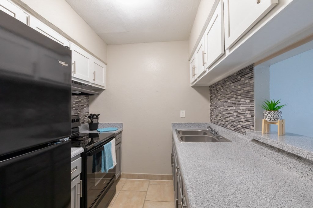 a kitchen with granite counter tops and a black refrigerator and sink