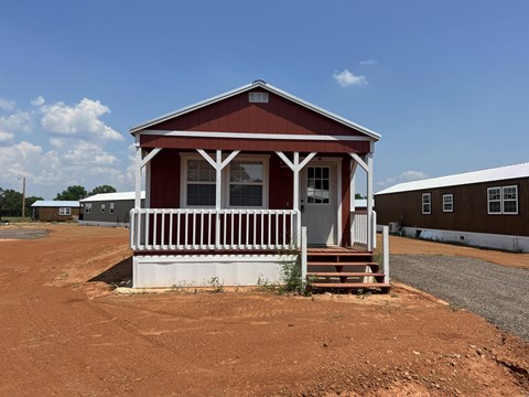 A small red house with white trim and a porch.