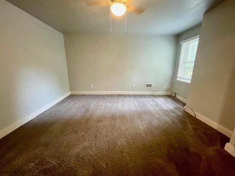 a empty living room with a carpeted floor and a ceiling fan