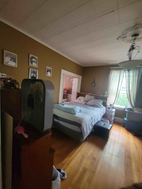 A bedroom with a bed, dresser, and ceiling fan.