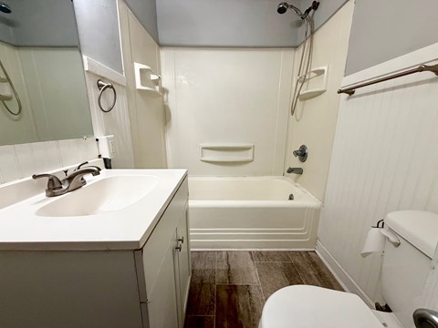 A white bathroom with a toilet, sink, and bathtub.