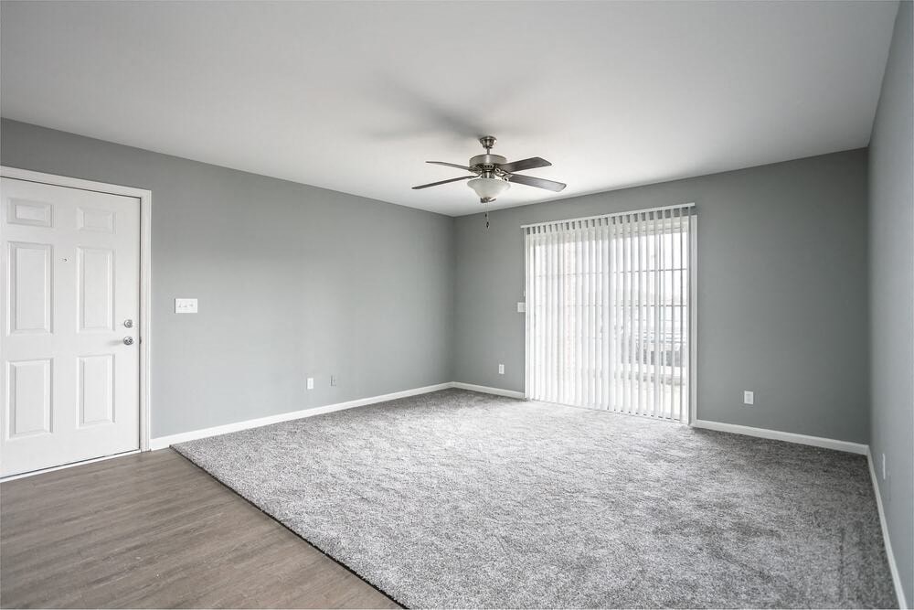 A room with a ceiling fan and a rug on the floor.