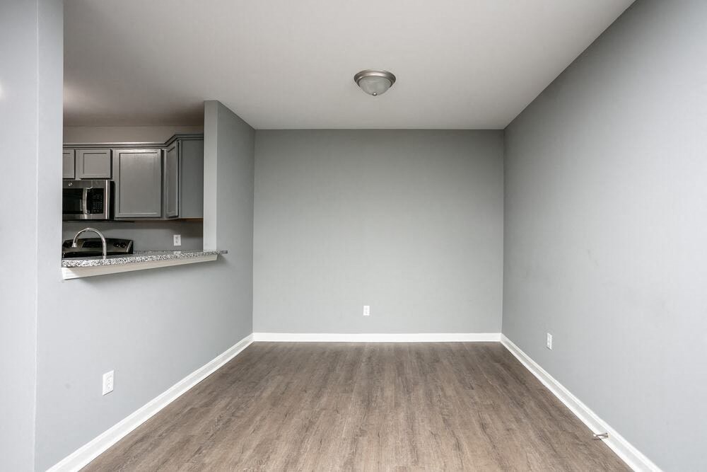 A room with a wooden floor and a wall-mounted microwave.