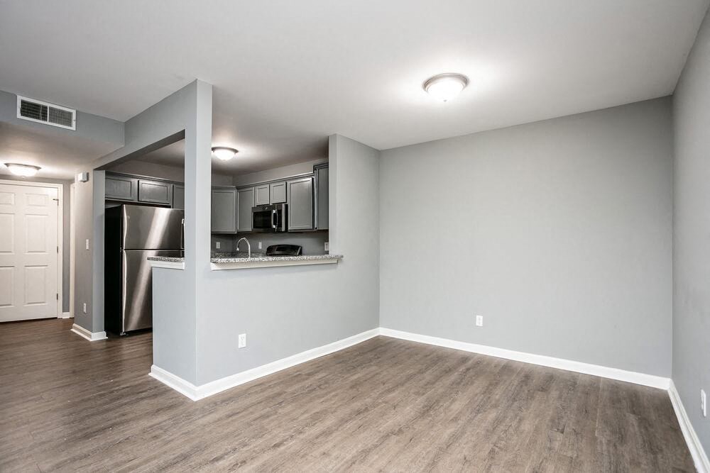 A kitchen area with a refrigerator, sink, and cabinets.