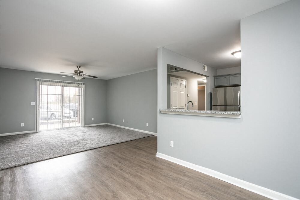 A spacious room with a ceiling fan and a window with blinds.