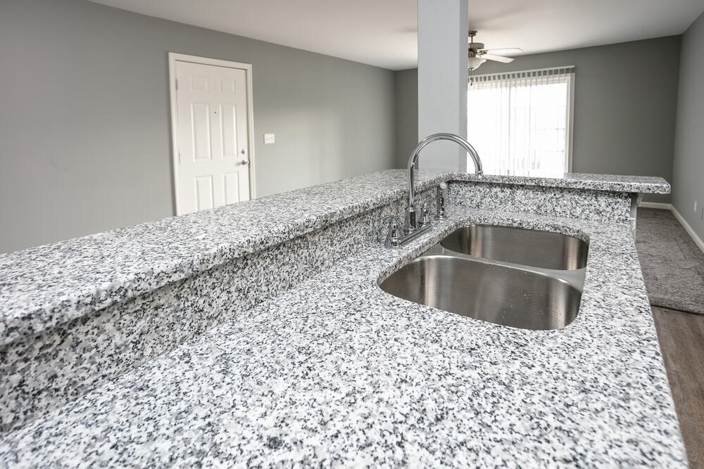 A kitchen counter with a sink and a door in the background.