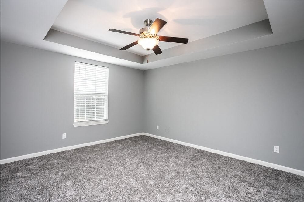 A room with a ceiling fan and a window with blinds.