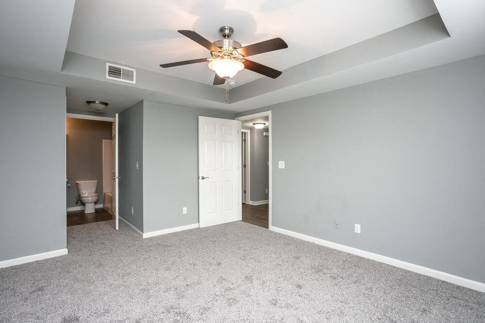 A room with a ceiling fan and carpeted floor.