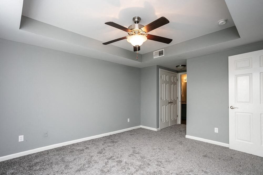 A room with a ceiling fan and carpeted floor.