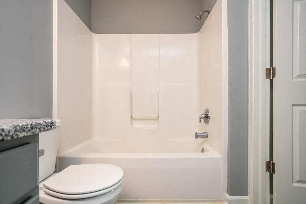 A white toilet sits next to a bathtub in a bathroom.