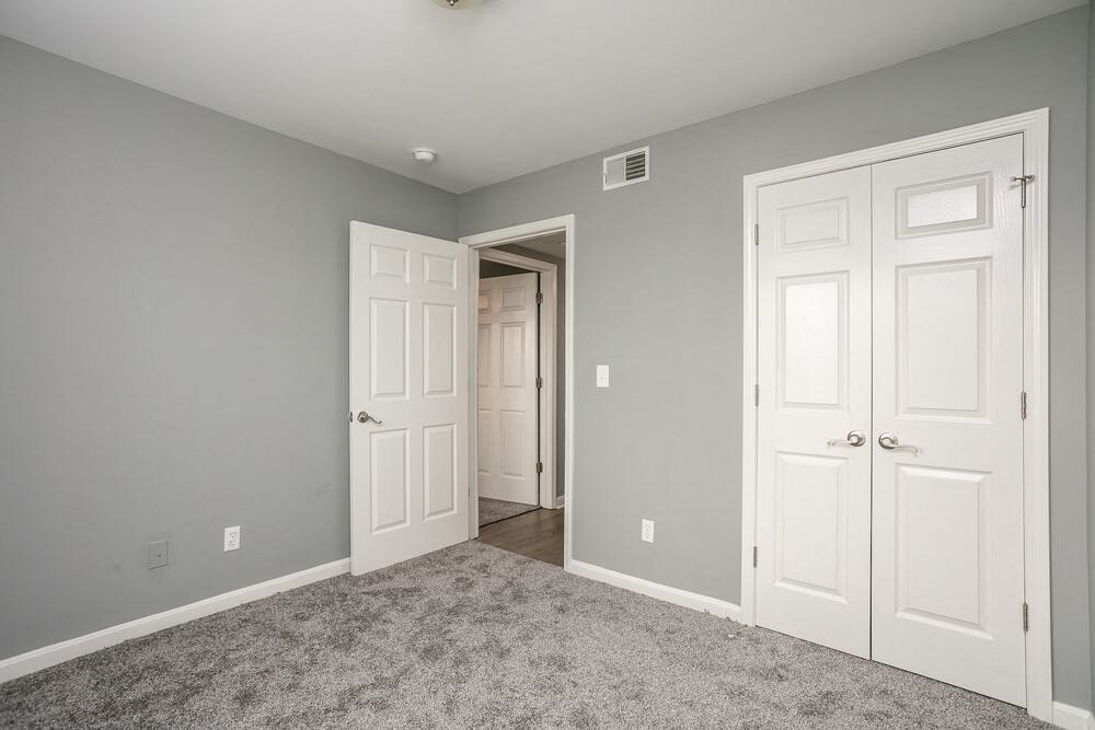 A room with two white doors and a carpeted floor.