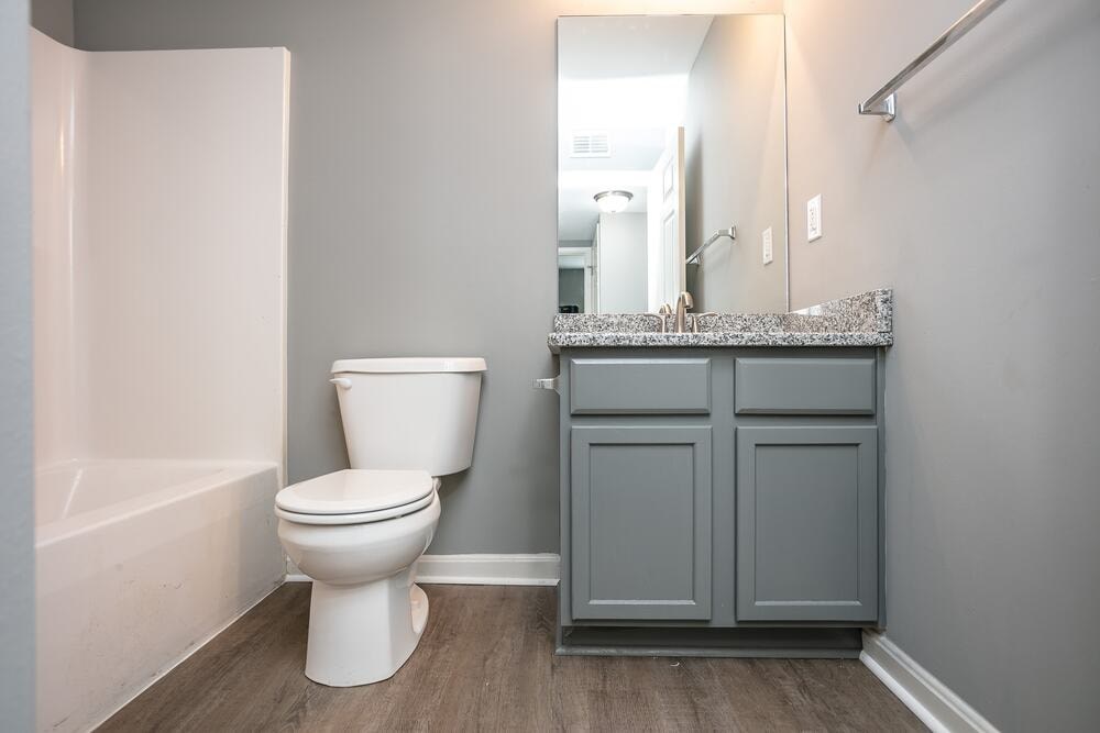 A white toilet sits in a bathroom next to a bathtub.