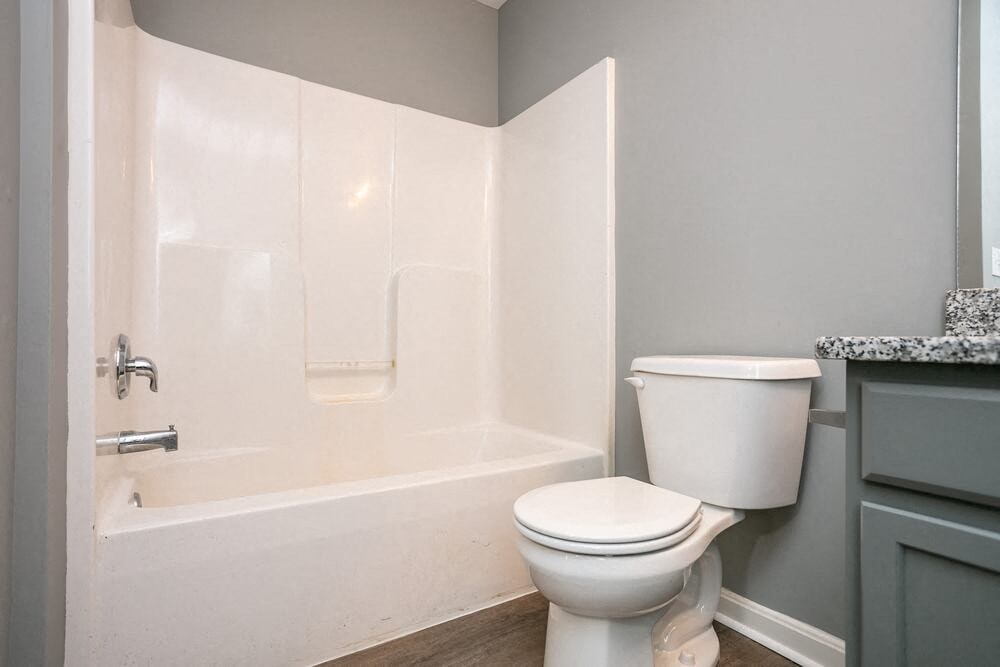 A white toilet sits next to a bathtub in a bathroom.