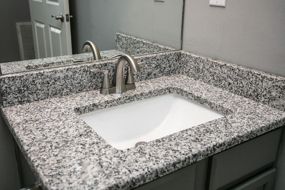 A bathroom sink with a granite countertop and a silver faucet.