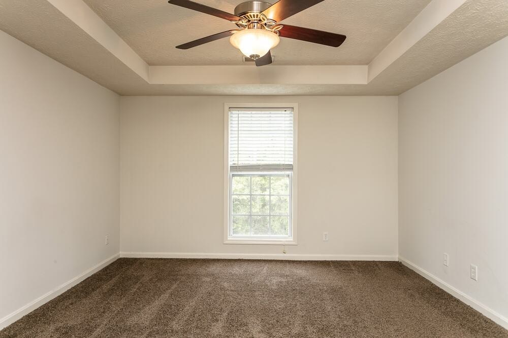 A room with a ceiling fan and carpeted floor.