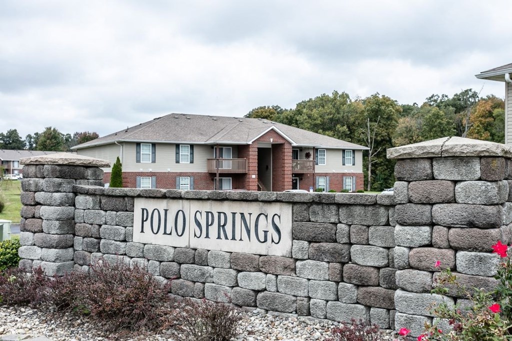 A stone wall with a sign that says Polo Springs.