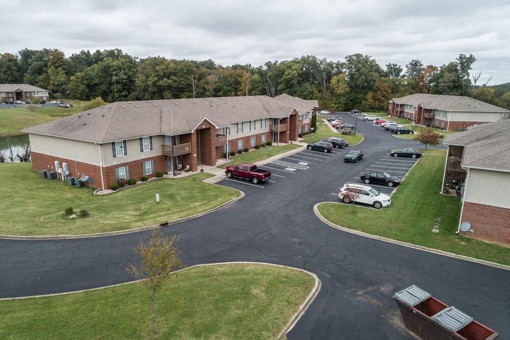 A view of a roundabout with cars driving through it and apartment buildings surrounding it.