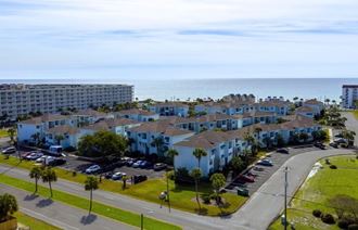 an aerial view of an apartment complex with the ocean in the background