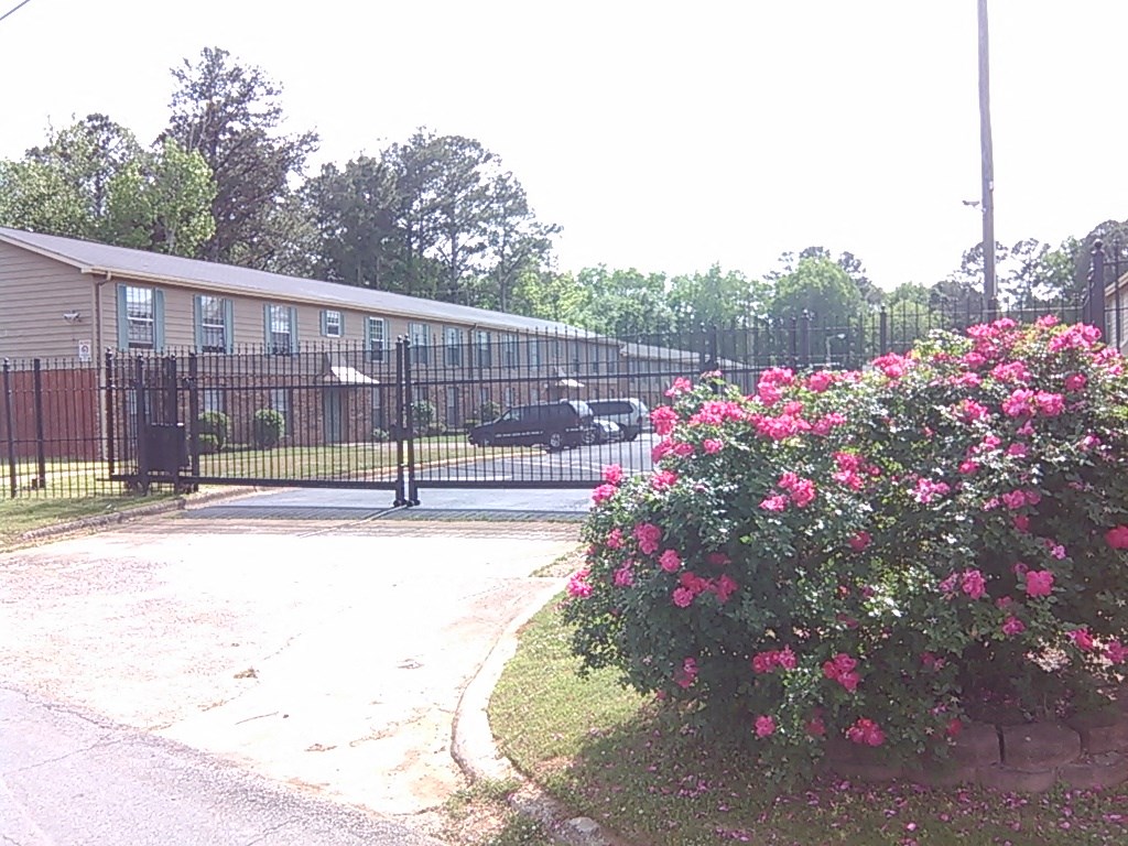 a house with a black fence and a bush with pink flowers