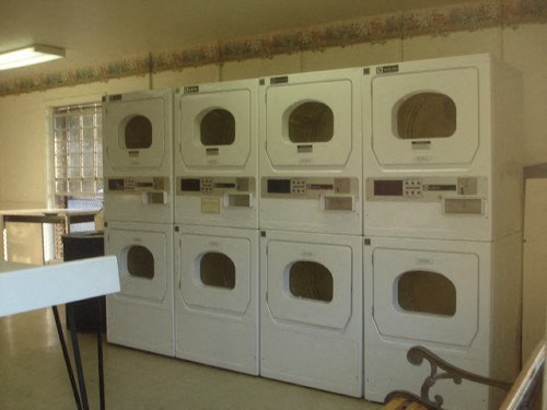 a row of white washer and dryers in a room