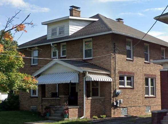 A two-story brick house with a white roof and a covered porch.
