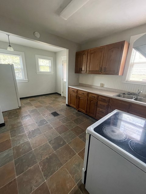 A kitchen with a white dishwasher and brown cabinets.