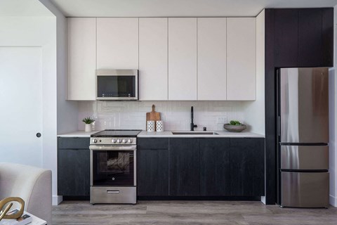 A modern kitchen with a stainless steel refrigerator and a microwave above the stove.