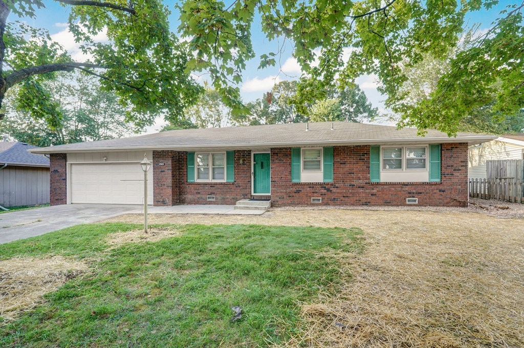 a brick house with a green door and a lawn