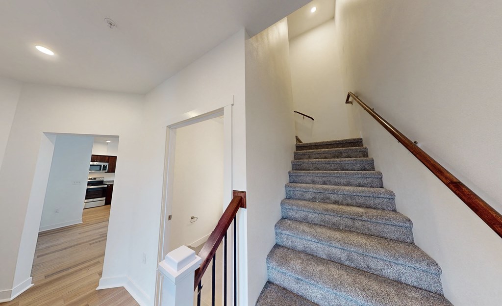 a staircase in a house with carpeted stairs and a door to a hallway